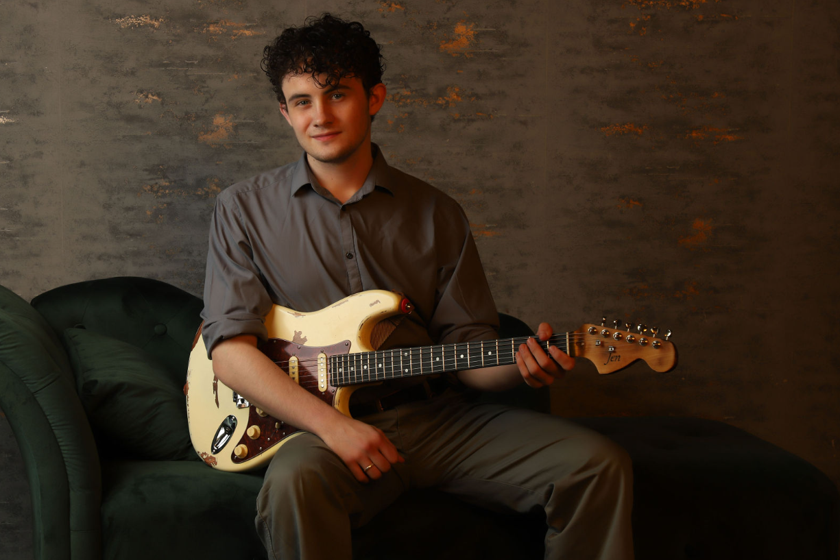 Harvey seated with guitar